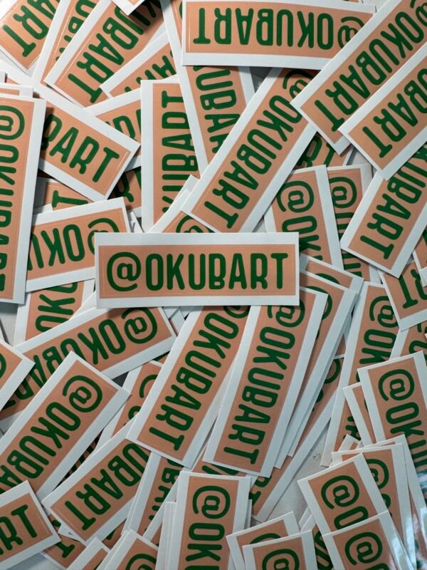@OKUBART 3x1 inch die-cut promotional sticker featuring green text on a peach background.