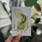 Yellow-green Japanese traditional tattoo-style catfish with a playful smile, painted in watercolor on 4x6 200 GSM fine art photographic paper