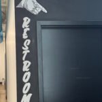 large scale mural painting in Joliet Illinois on interior wall featuring 'restroom' and a hand pointing directionally